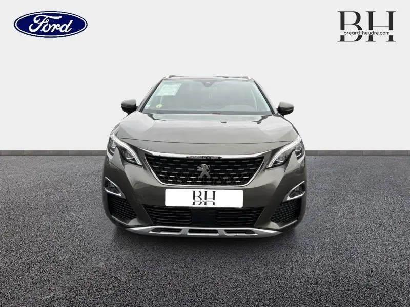 Vue frontale d'un Peugeot 5008 gris Amazonite avec calandre noire et détails chromés, sur fond neutre.