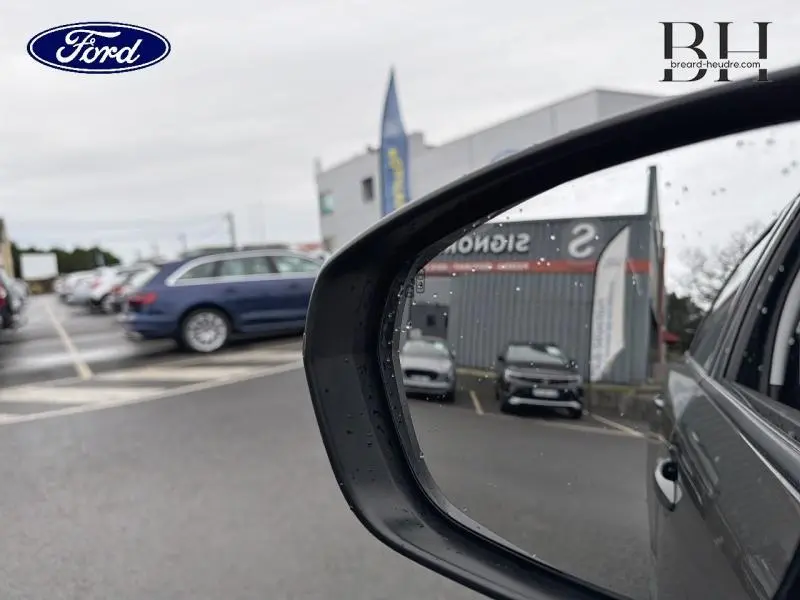 Rétroviseur extérieur droit d’un Peugeot 5008 gris Amazonite, vue partielle avec reflet de voitures en arrière-plan.