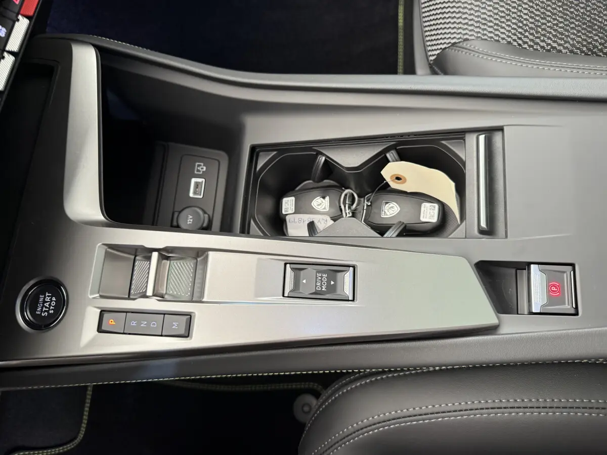 Vue rapprochée de la console centrale grise de la Peugeot 308 Hybrid 136 e-DCS6 GT avec clé et bouton start/stop.