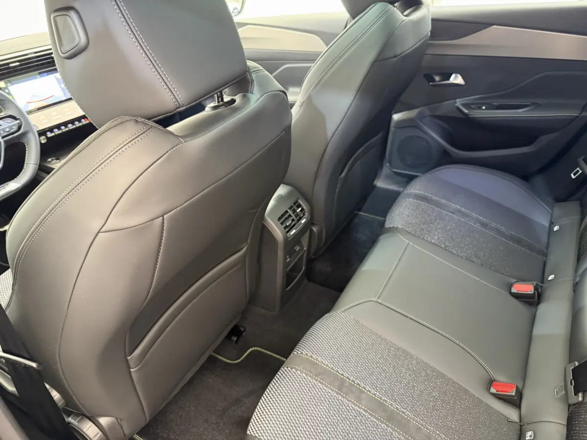 Vue intérieure arrière droite de la Peugeot 308 Hybrid 136 e-DCS6 GT 2024, sièges en cuir noir et tissu gris.