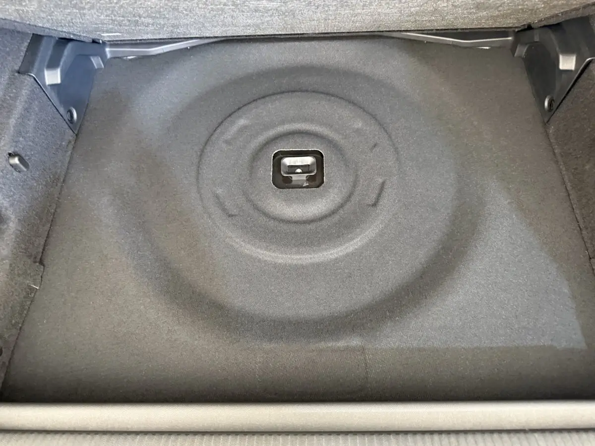 Vue plongeante sur le coffre vide de la Peugeot 308 Hybrid 136 e-DCS6 GT, revêtement gris foncé sans roue de secours visible.