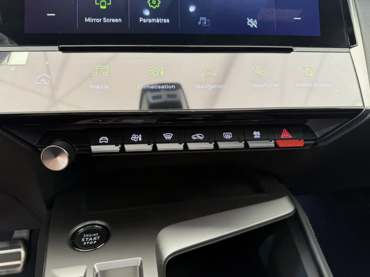 Vue rapprochée du tableau de bord noir du Peugeot 308 Hybrid 2024, avec écran tactile et boutons de commande éclairés.