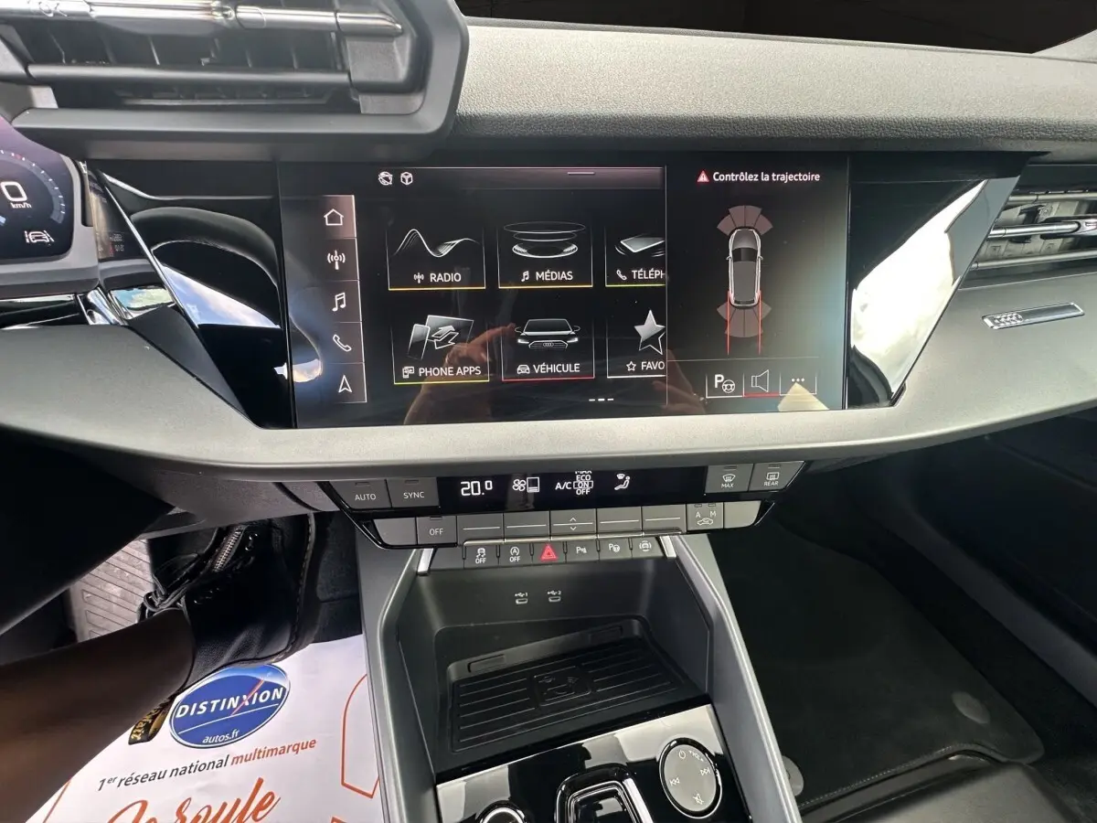Vue intérieure centrée sur la console centrale et l’écran tactile de l’Audi A3 30 TFSI blanc, affichant les commandes multimédia.