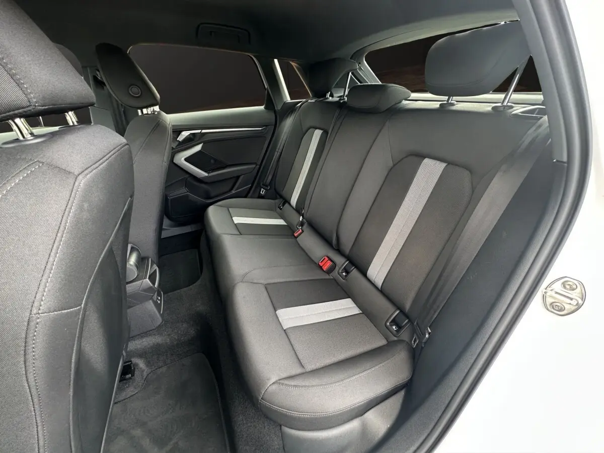 Vue intérieure côté droit des sièges arrière en tissu gris avec bandes claires de l'Audi A3 blanche 2024.