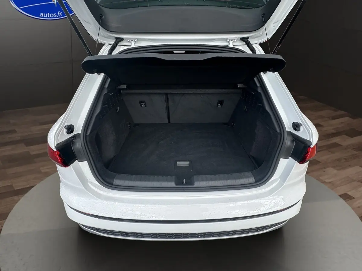 Coffre ouvert vu de l'arrière d'une Audi A3 blanche 2024, mettant en valeur l'espace de chargement intérieur noir.