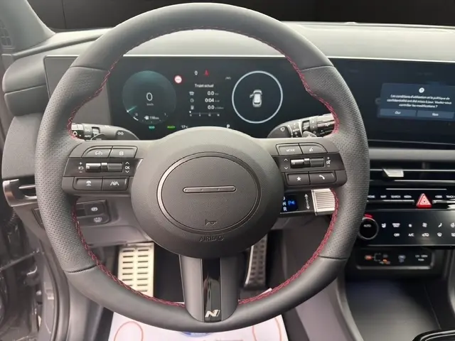 Vue intérieure centrée sur le volant cuir noir avec surpiqûres rouges du Hyundai Tucson 1.6 Hybrid N Line 2026.