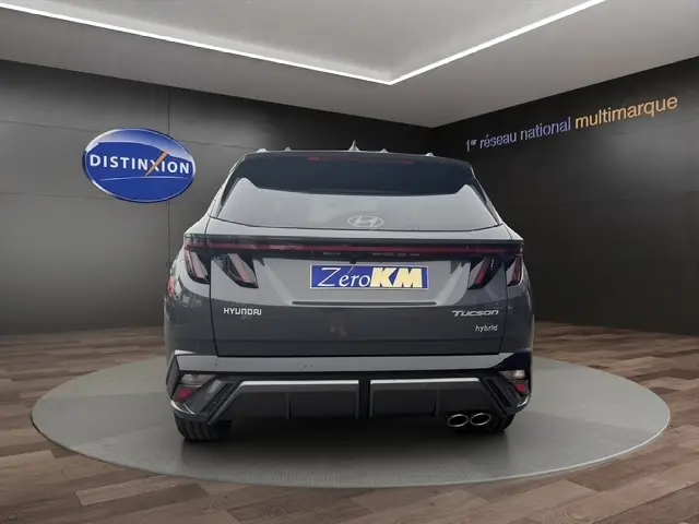 Vue arrière d'un Hyundai Tucson gris foncé 2026 avec hayon motorisé et double sortie d'échappement visible.