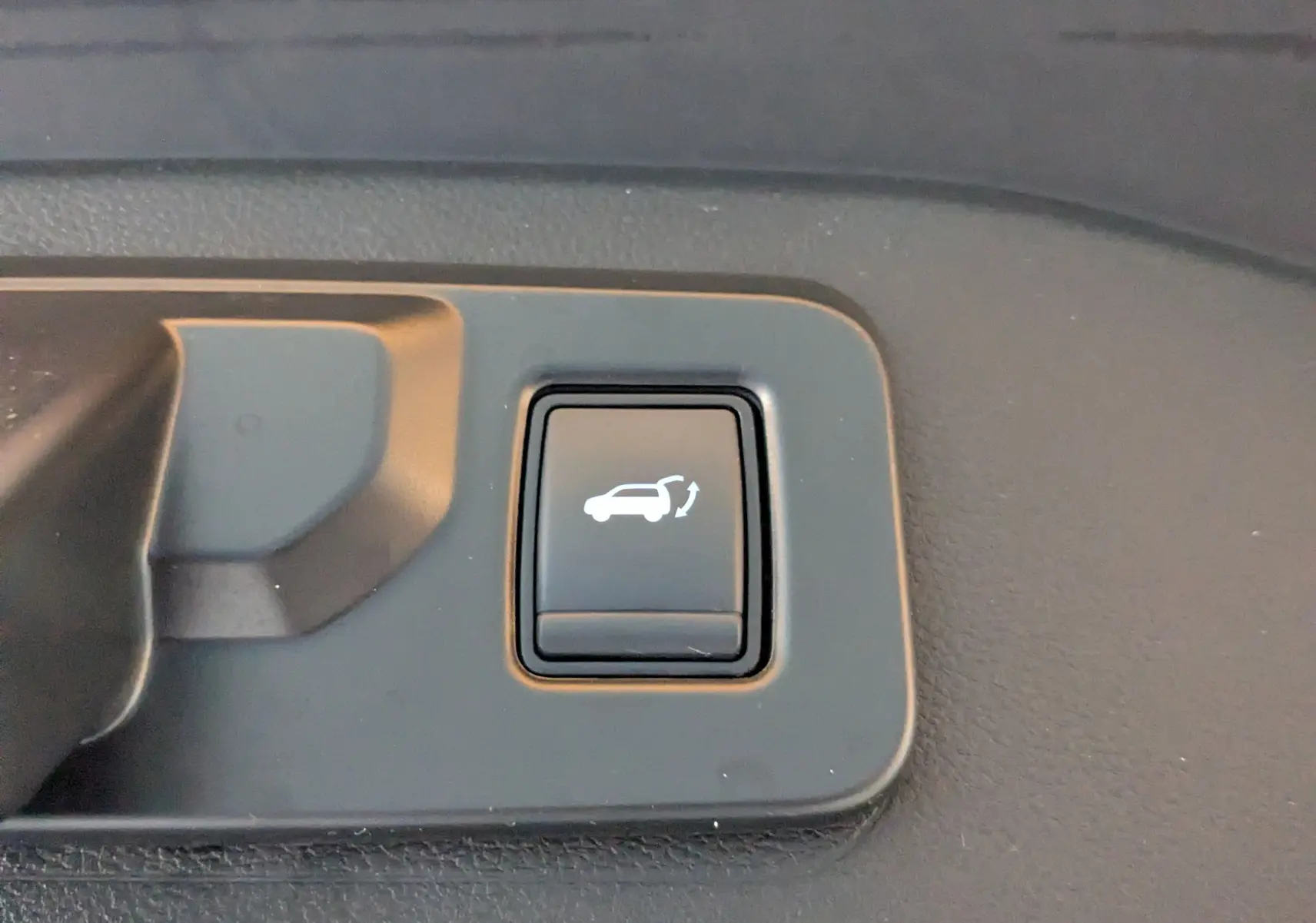 Gros plan sur le bouton intérieur noir d'ouverture électrique du hayon du Renault Espace VI E-Tech Full Hybrid 2025.