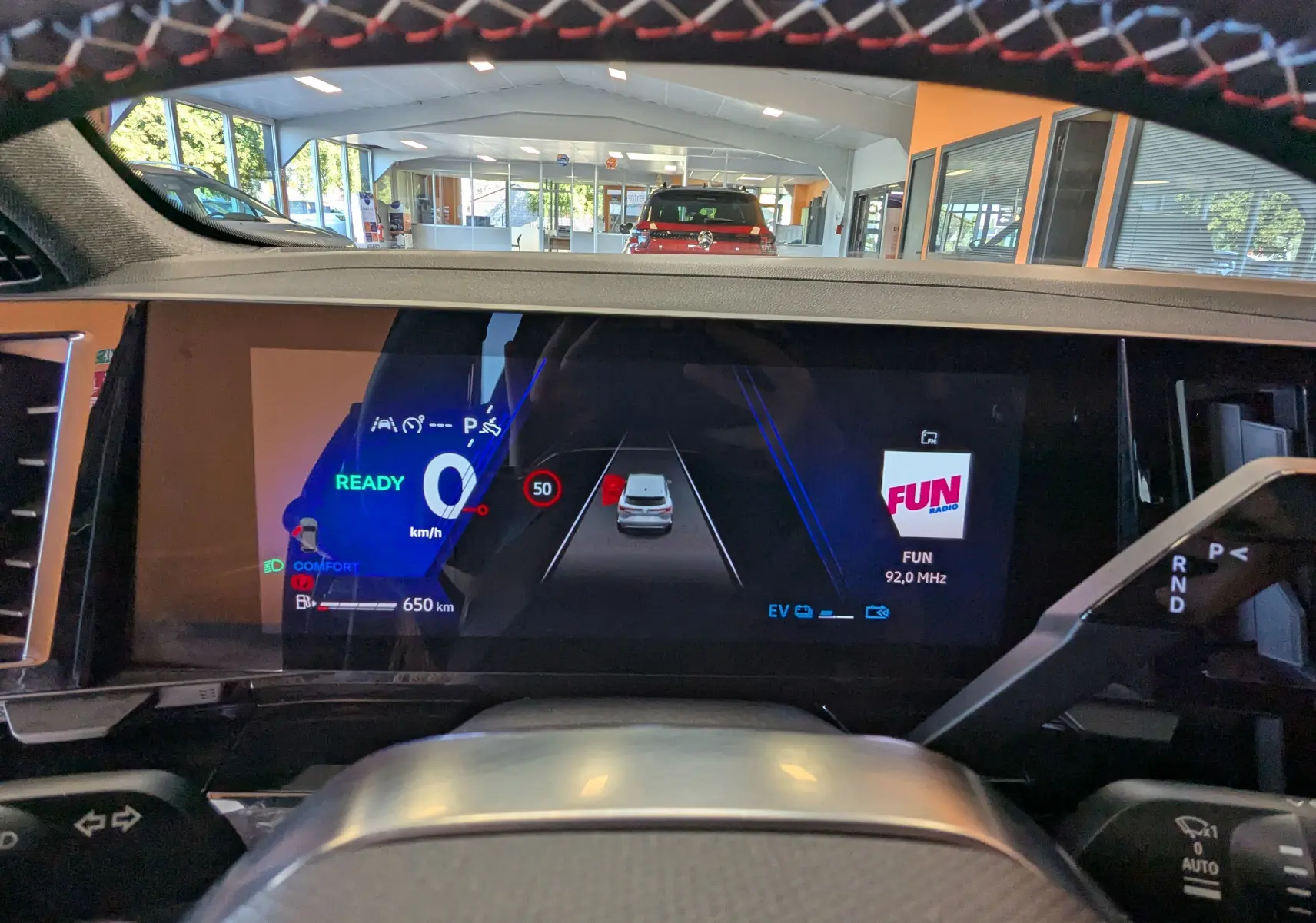 Vue intérieure du tableau de bord numérique du Renault Espace VI hybride, affichant la vitesse à 0 km/h et la radio FUN.
