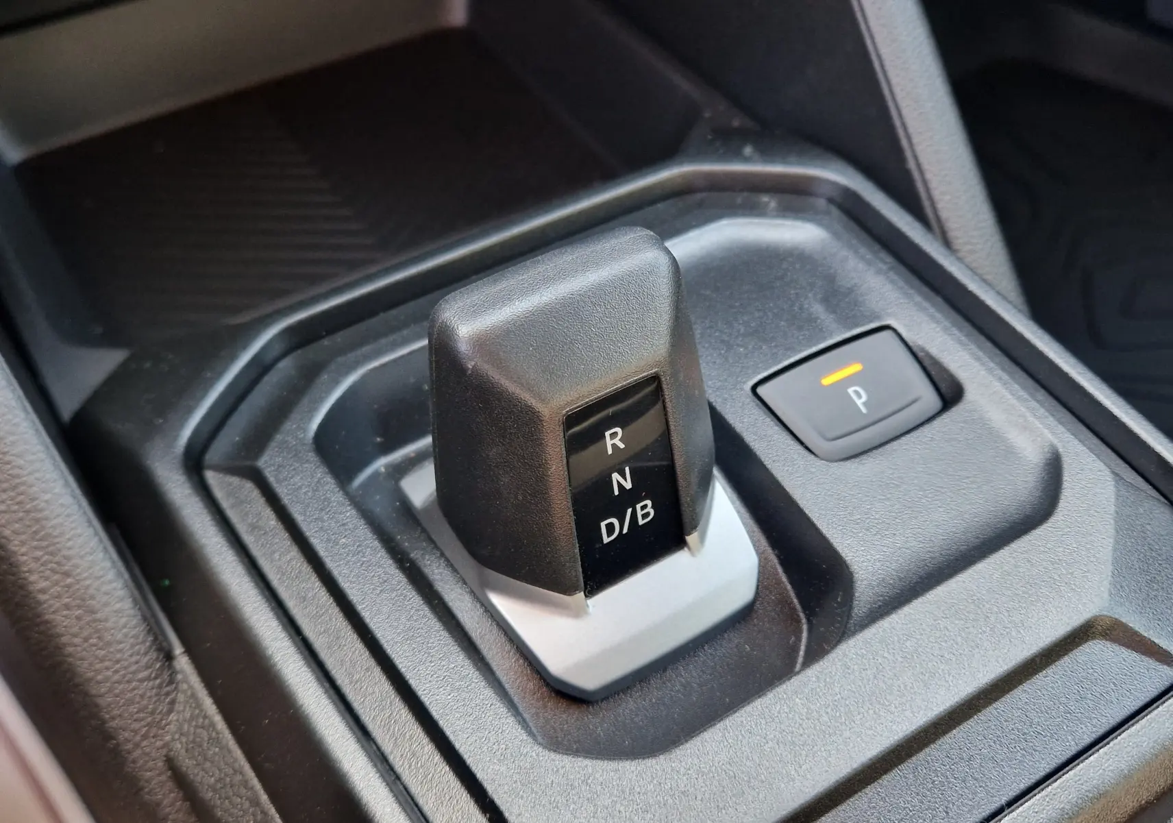Gros plan sur le sélecteur de boîte automatique noir et gris du Dacia Duster 1.8 Hybrid 155, avec bouton de parking éclairé.