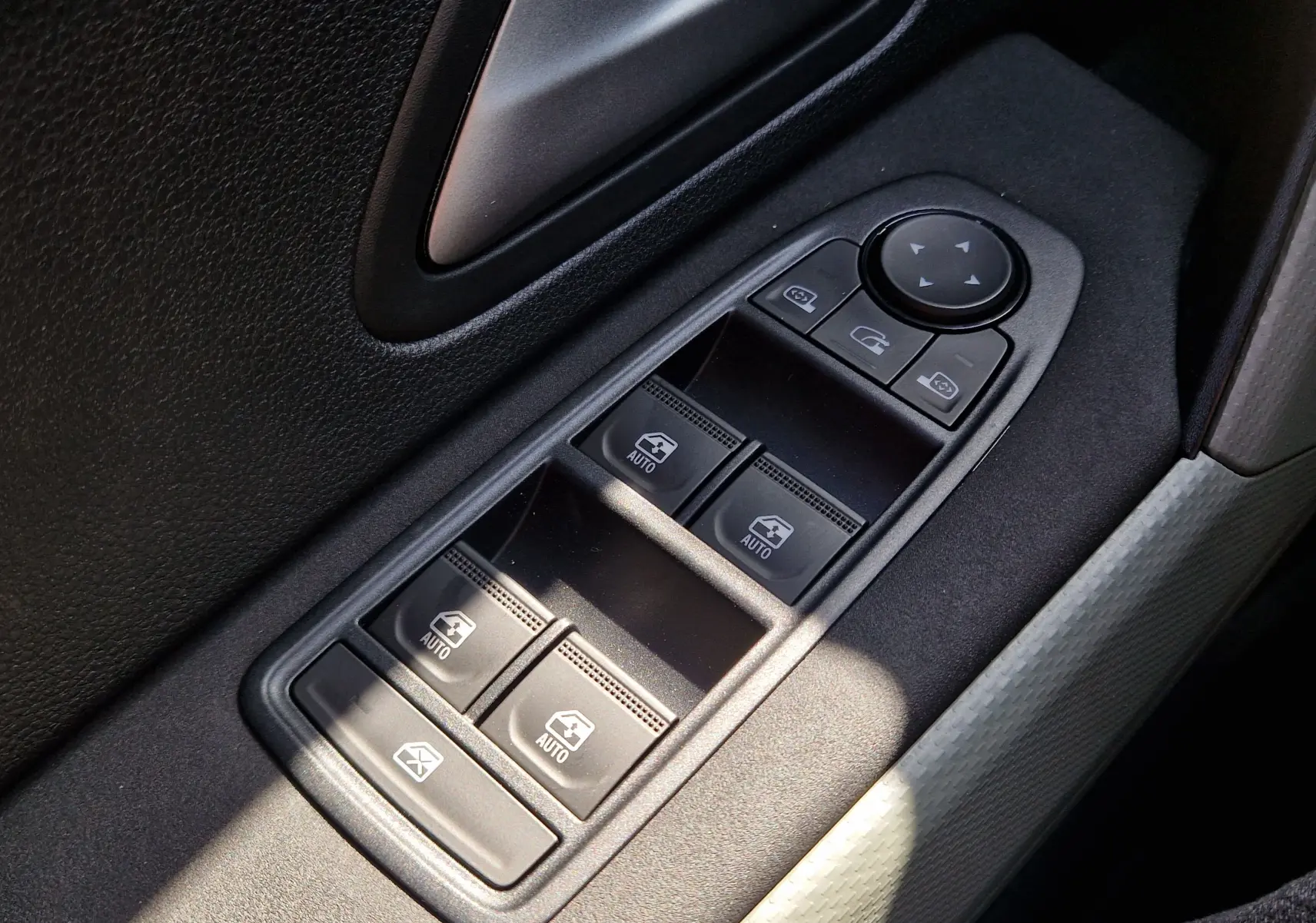 Gros plan sur les commandes de lève-vitres et rétroviseurs côté gauche intérieur du Dacia Duster 2026, finition noire.