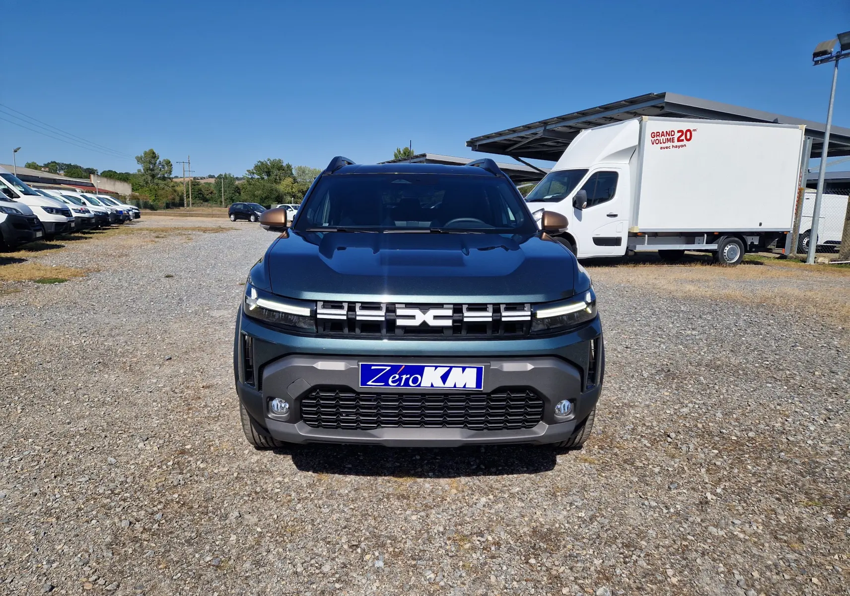 Vue frontale d'un Dacia Duster 1.8 Hybrid 155 Extreme vert cèdre, avec calandre moderne et plaques "Zéro KM".