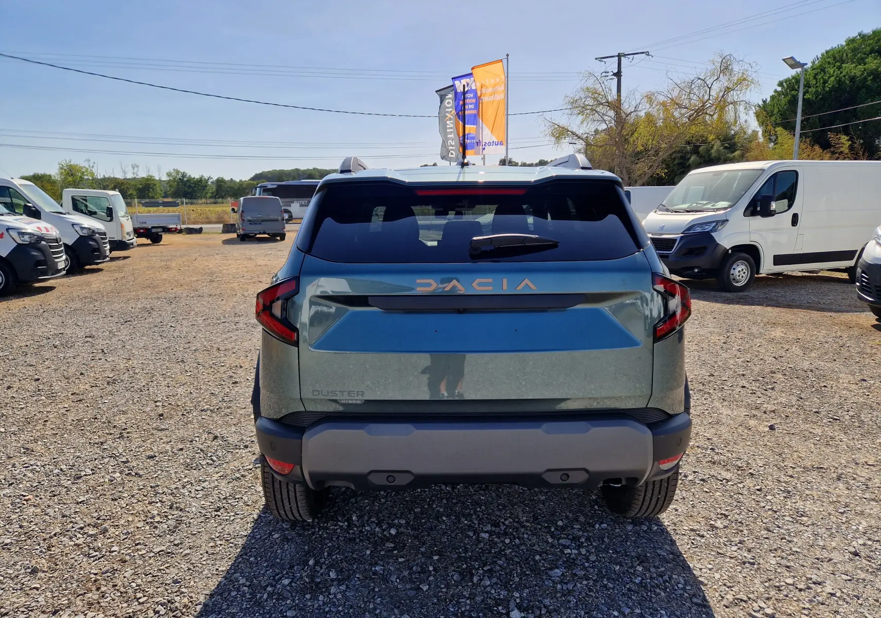 Vue arrière d’un Dacia Duster 1.8 Hybrid 155 en vert cèdre, avec logo DACIA et feux arrière distinctifs.