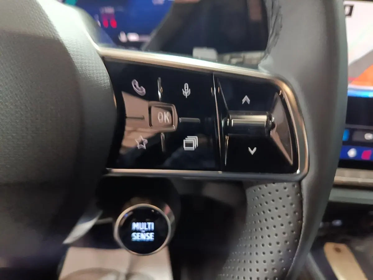 Gros plan sur les commandes multifonctions en cuir du volant du Renault Austral 2024, avec bouton rotatif Multi Sense.
