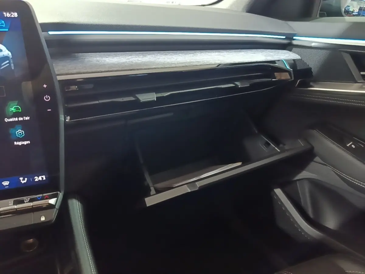 Intérieur du Renault Austral 2024, vue côté passager sur la boîte à gants ouverte et le tableau de bord noir avec inserts bois.