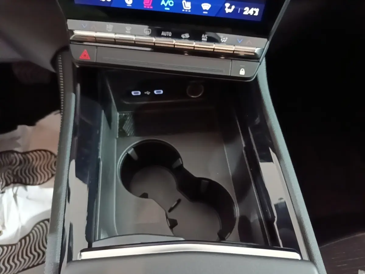 Gros plan sur la console centrale noire du Renault Austral 2024 avec porte-gobelets et commandes tactiles visibles.