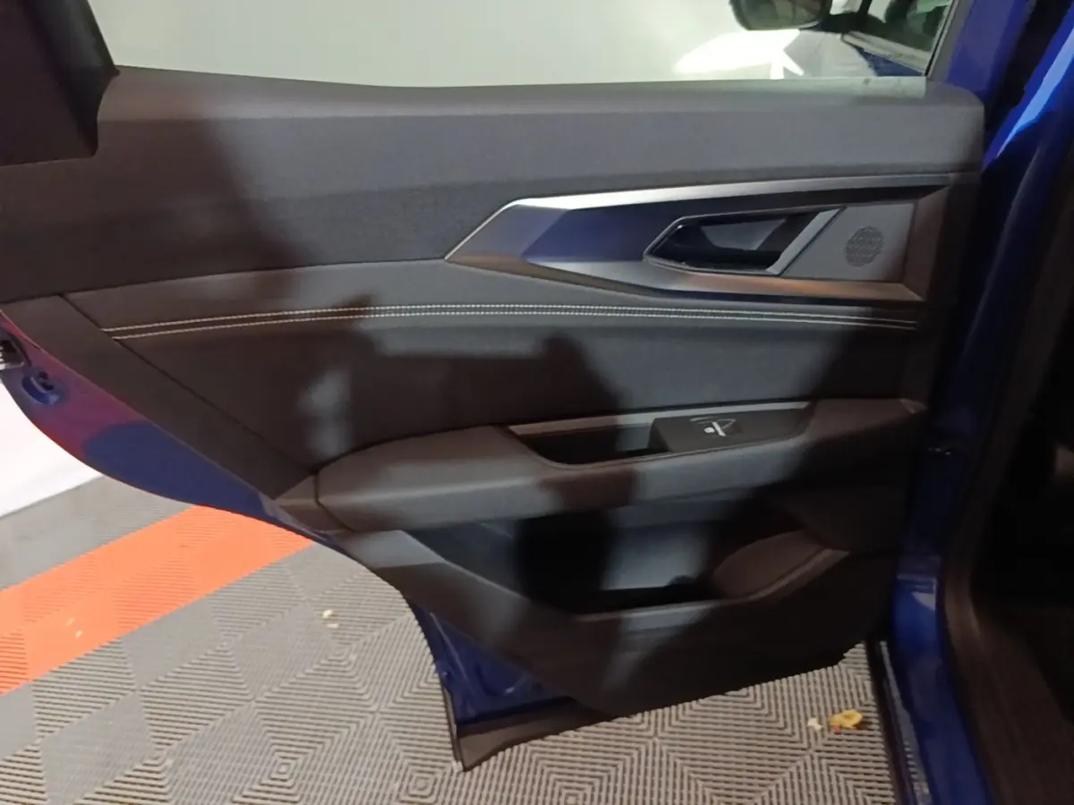 Vue rapprochée de la porte avant gauche bleu du Renault Austral 2024, montrant la poignée et les commandes de fenêtre.