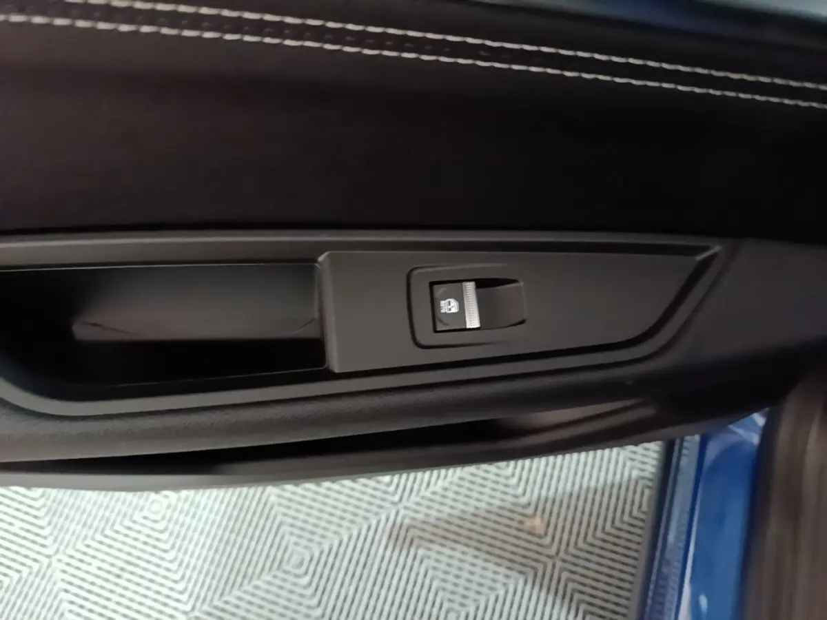 Détail de la commande d'éclairage sur la porte côté conducteur du Renault Austral bleu 2024, intérieur noir.