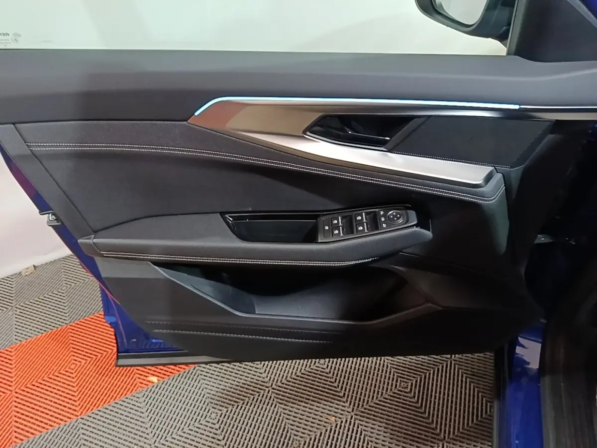 Vue rapprochée de la porte avant gauche bleu Renault Austral 2024 avec commandes de vitres et éclairage d'ambiance.