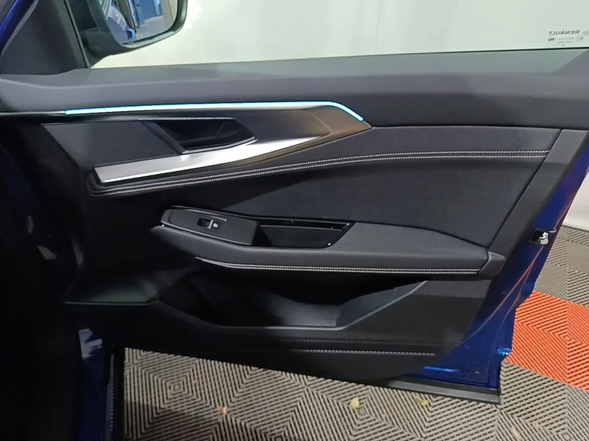 Vue intérieure de la porte avant gauche bleu Renault Austral 2024 avec éclairage d'ambiance et finitions tissu et métal.