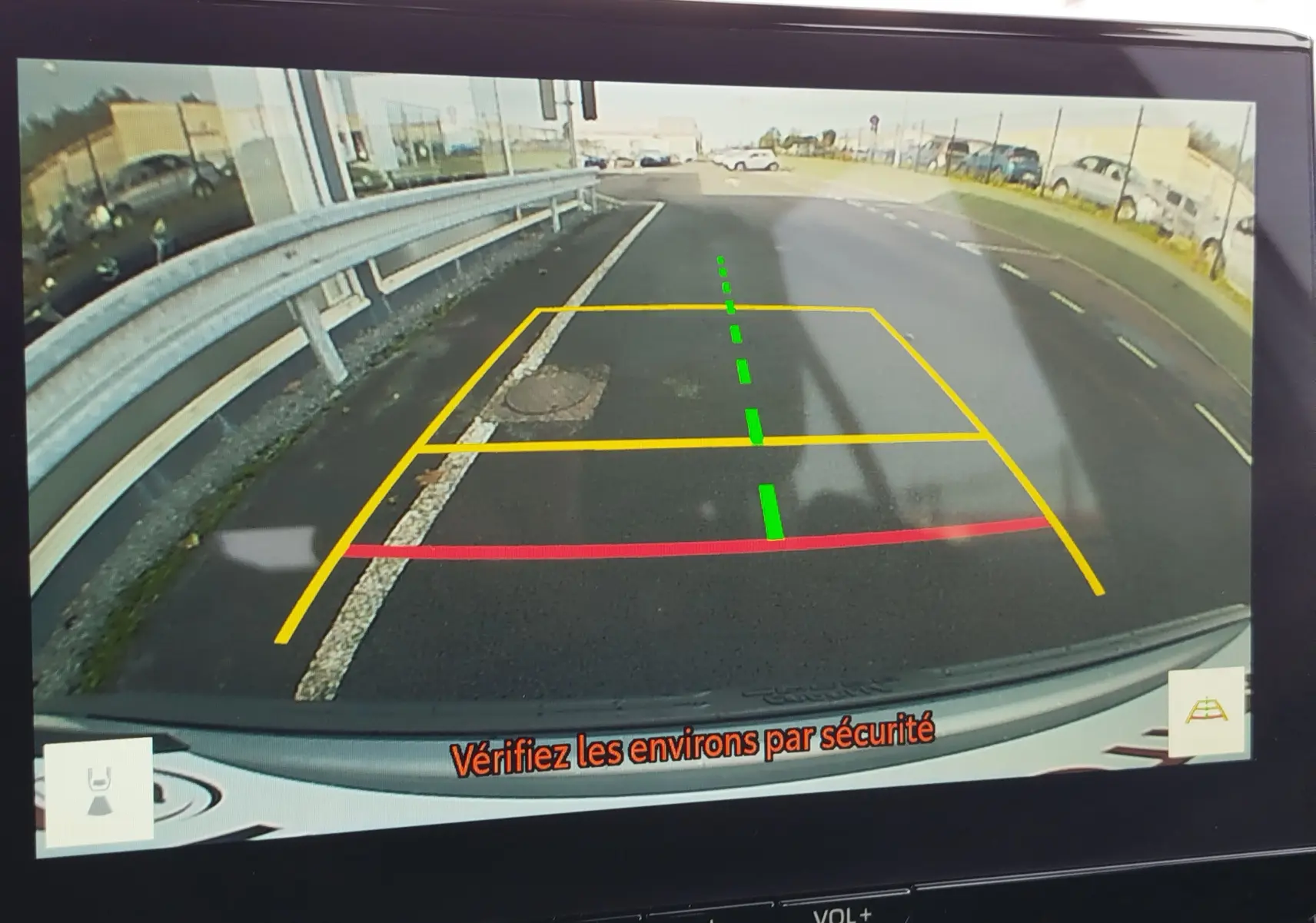 Vue caméra de recul du Toyota Corolla Cross gris acier 2025, avec lignes de guidage colorées et message de sécurité.