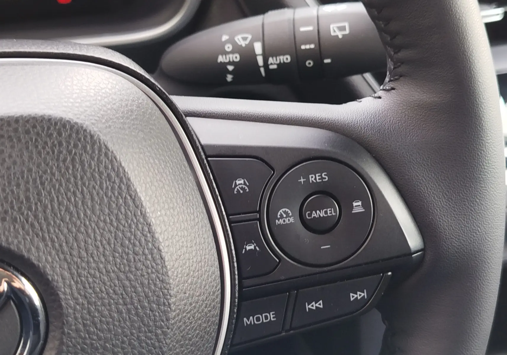 Détail du volant côté droit de la Toyota Corolla Cross gris acier 2025, avec commandes de régulateur et mode audio.