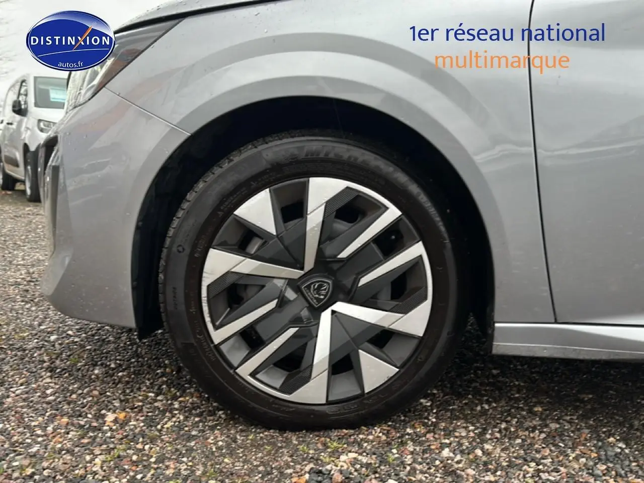 Gros plan sur la roue avant gauche d'une Peugeot 208 gris artense, mettant en valeur la jante au design géométrique.