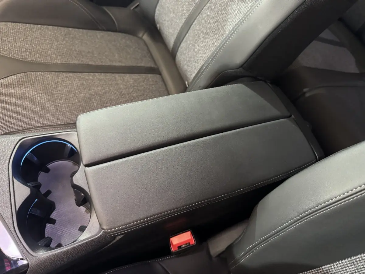 Gros plan sur l'accoudoir central noir et porte-gobelets du Peugeot 3008 PureTech 130 essence, intérieur tissu gris.