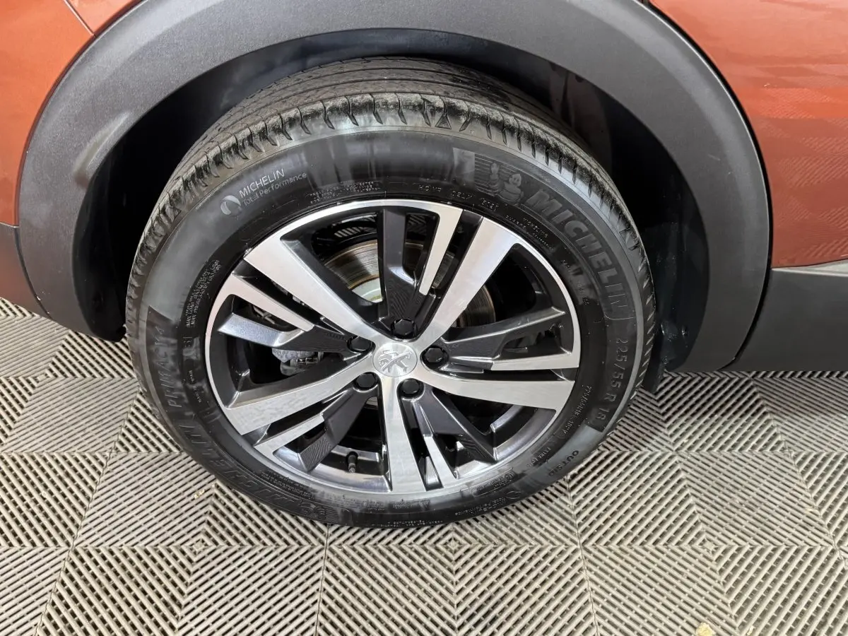 Gros plan sur la roue avant droite du Peugeot 3008 orange 2020 avec jante alliage bicolore et pneu Michelin.