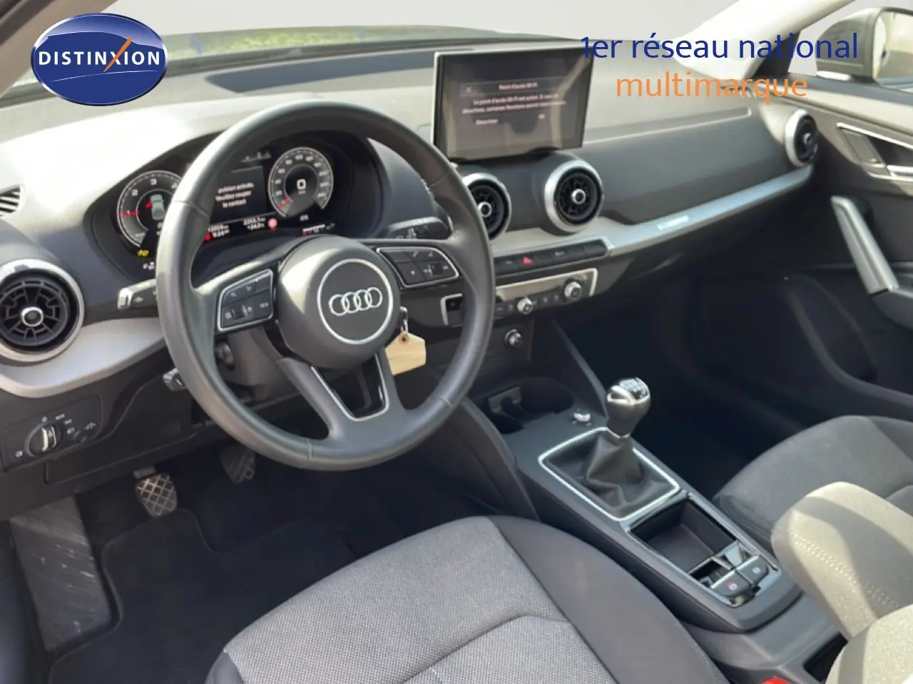 Vue intérieure côté conducteur de l'Audi Q2 30 TDI S-Line 2025, volant cuir, tableau de bord numérique et boîte manuelle.