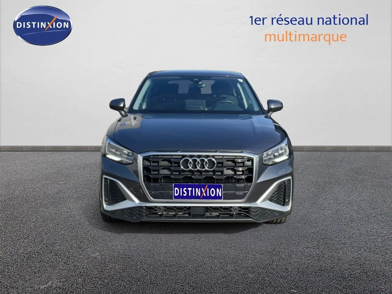 Vue frontale d'un Audi Q2 30 TDI S-Line gris Manhattan métallisé avec calandre noire et phares LED allumés.