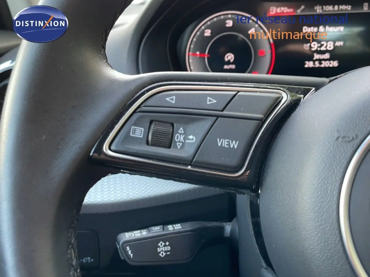 Gros plan sur le volant noir de l'Audi Q2 30 TDI S-Line 2025, avec commandes multifonctions et tableau de bord numérique en arrière-plan.