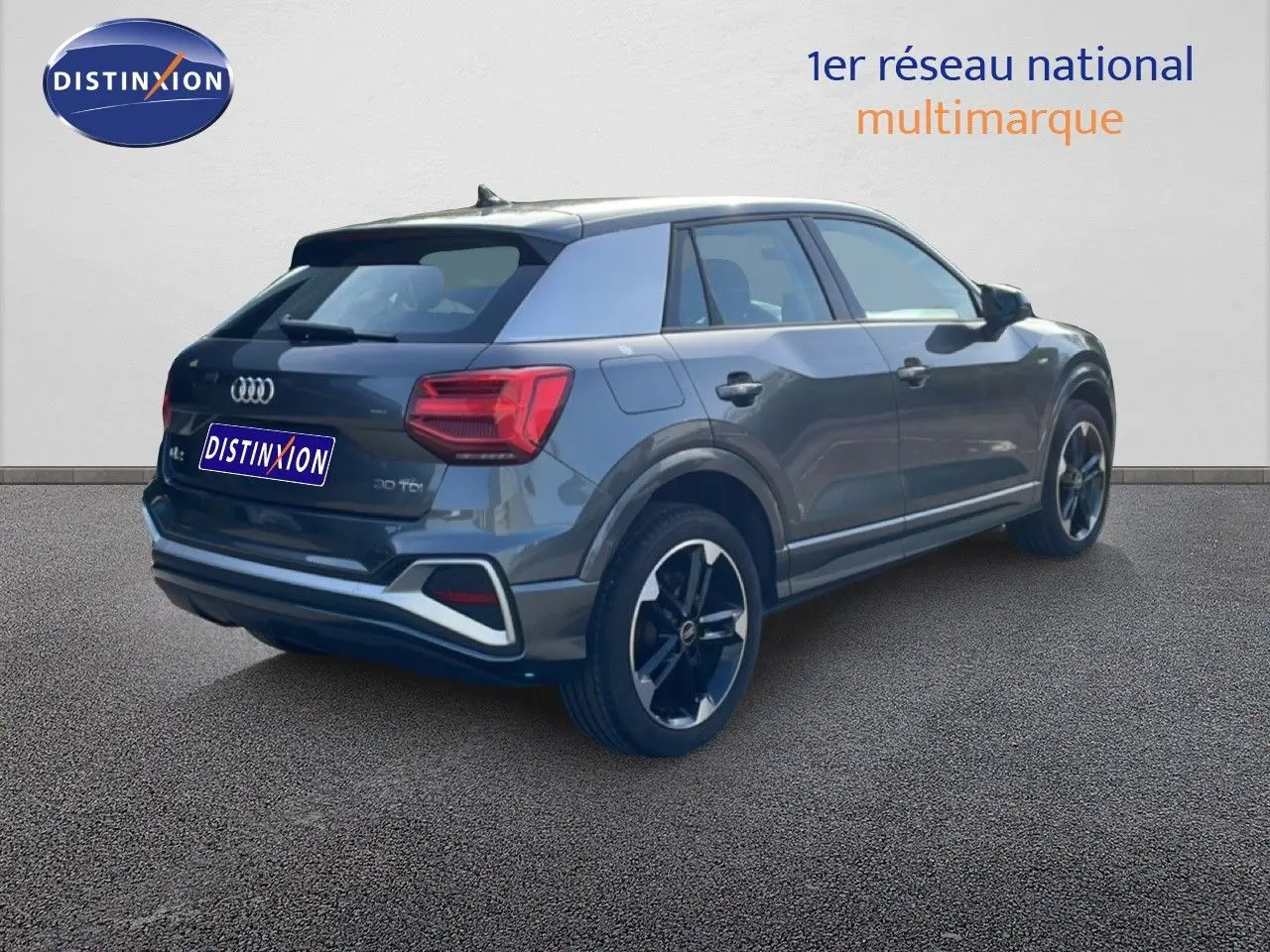 Audi Q2 30 TDI S-Line gris Manhattan métal, vue 3/4 arrière droit, jantes noires et feux arrière LED visibles.