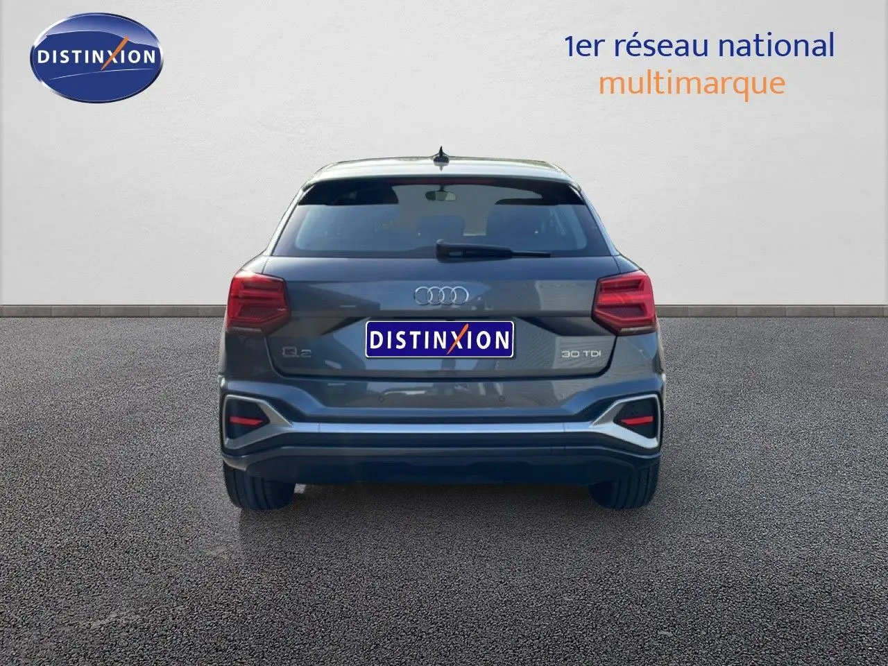 Vue arrière d'un Audi Q2 30 TDI S-Line gris Manhattan métal, mettant en valeur ses feux et son logo distinctifs.