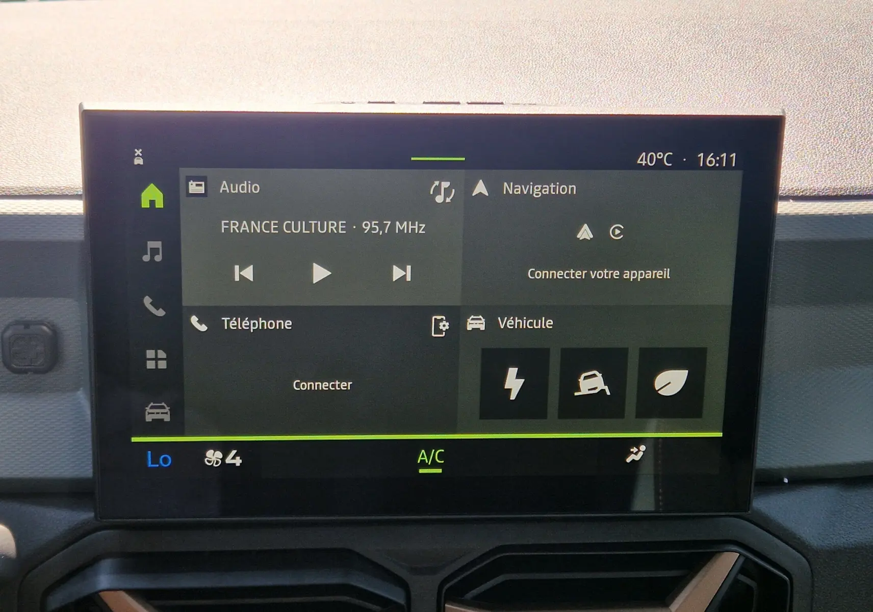 Écran tactile central du Dacia Duster 2026 blanc, affichant radio, navigation et options véhicule en intérieur.