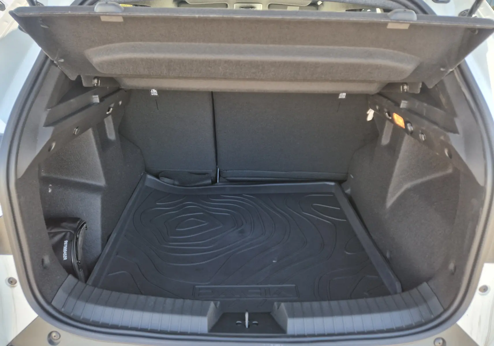 Coffre ouvert vu de l'arrière d'un Dacia Duster blanc 2026, avec tapis de protection noir et intérieur spacieux.