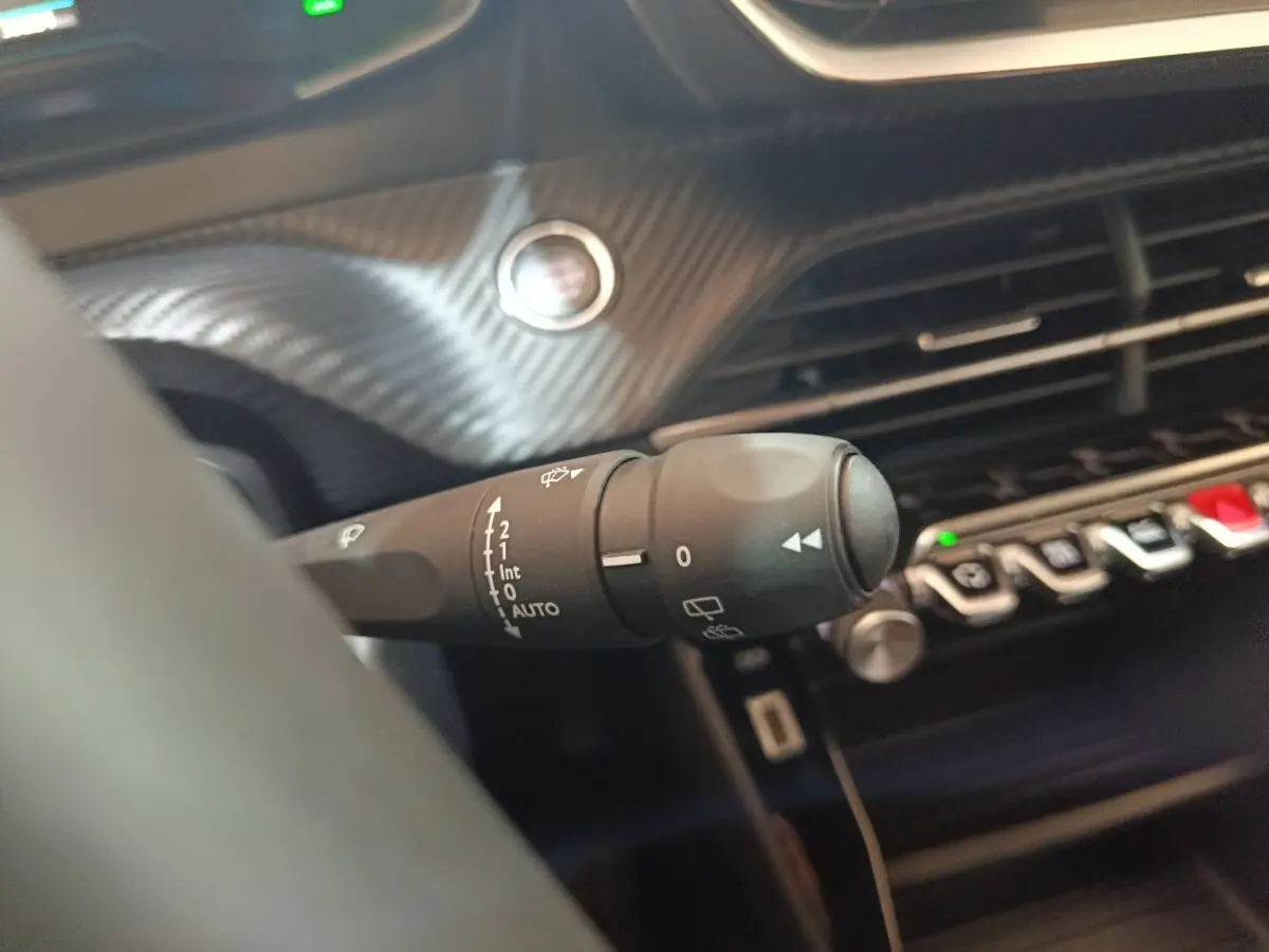 Gros plan sur la commande des essuie-glaces côté gauche du tableau de bord du Peugeot E-2008 électrique gris clair.