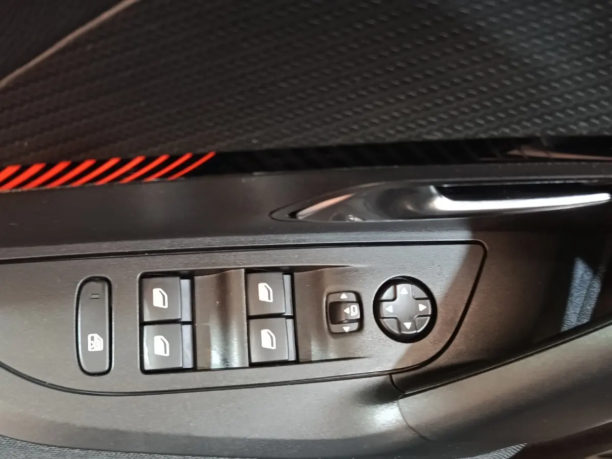 Gros plan sur les commandes des vitres électriques et rétroviseurs côté conducteur du Peugeot E-2008 électrique gris clair 2023.