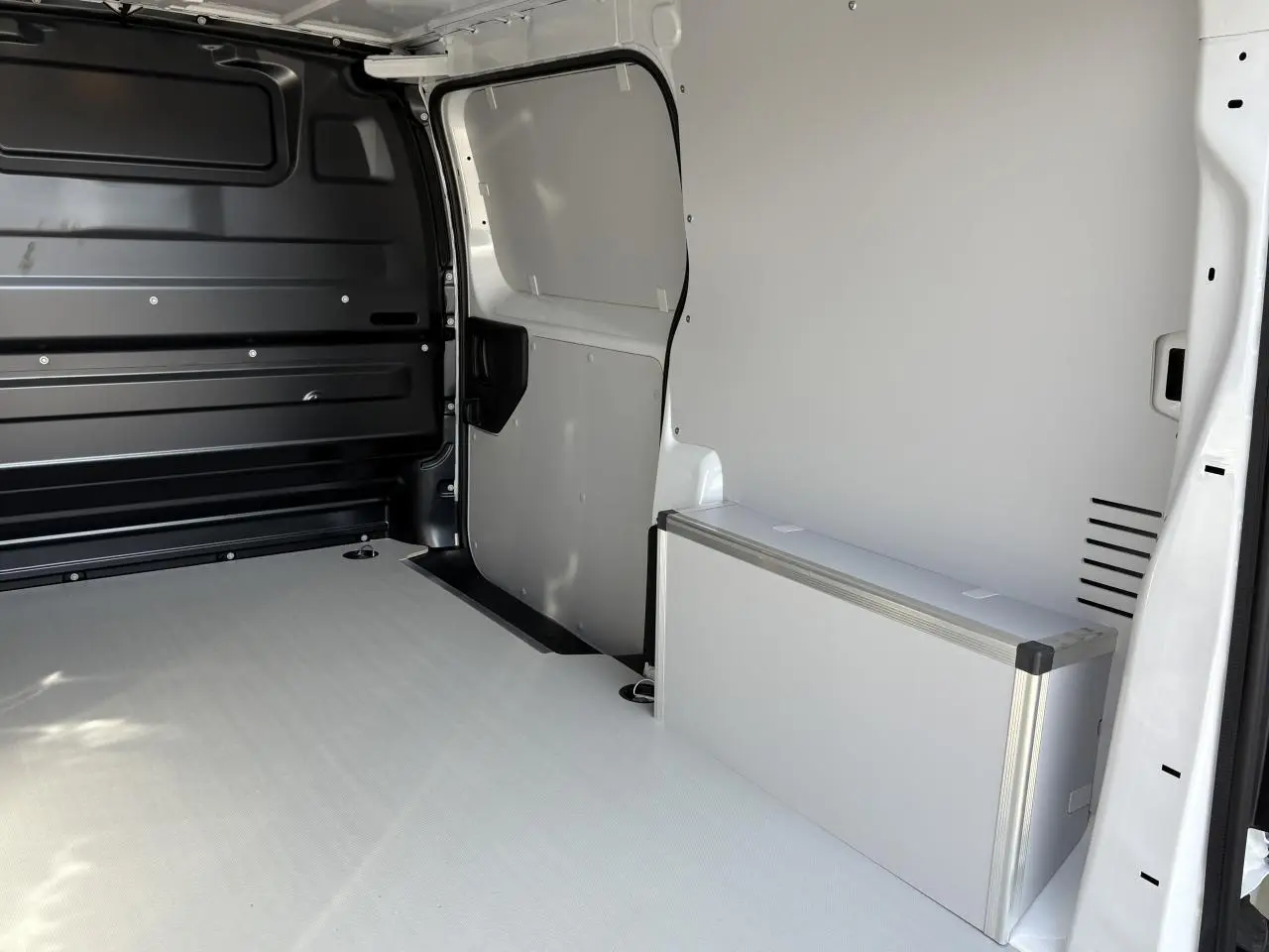Intérieur du coffre du fourgon blanc Opel Vivaro 2024, plancher et habillages latéraux en bois avec coffrage aluminium.