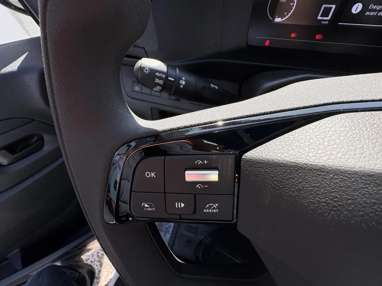 Gros plan sur les commandes au volant à gauche de l'Opel Vivaro blanc 2024, avec boutons de régulateur et assistance.