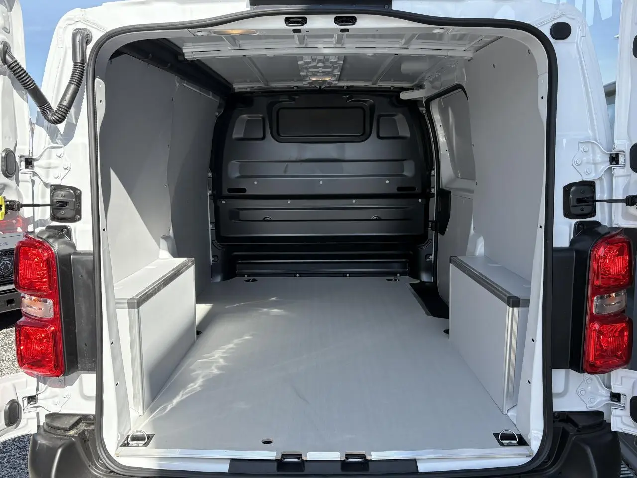 Vue arrière du fourgon blanc Opel Vivaro 2024, montrant l'espace de chargement avec plancher et habillages latéraux en bois.