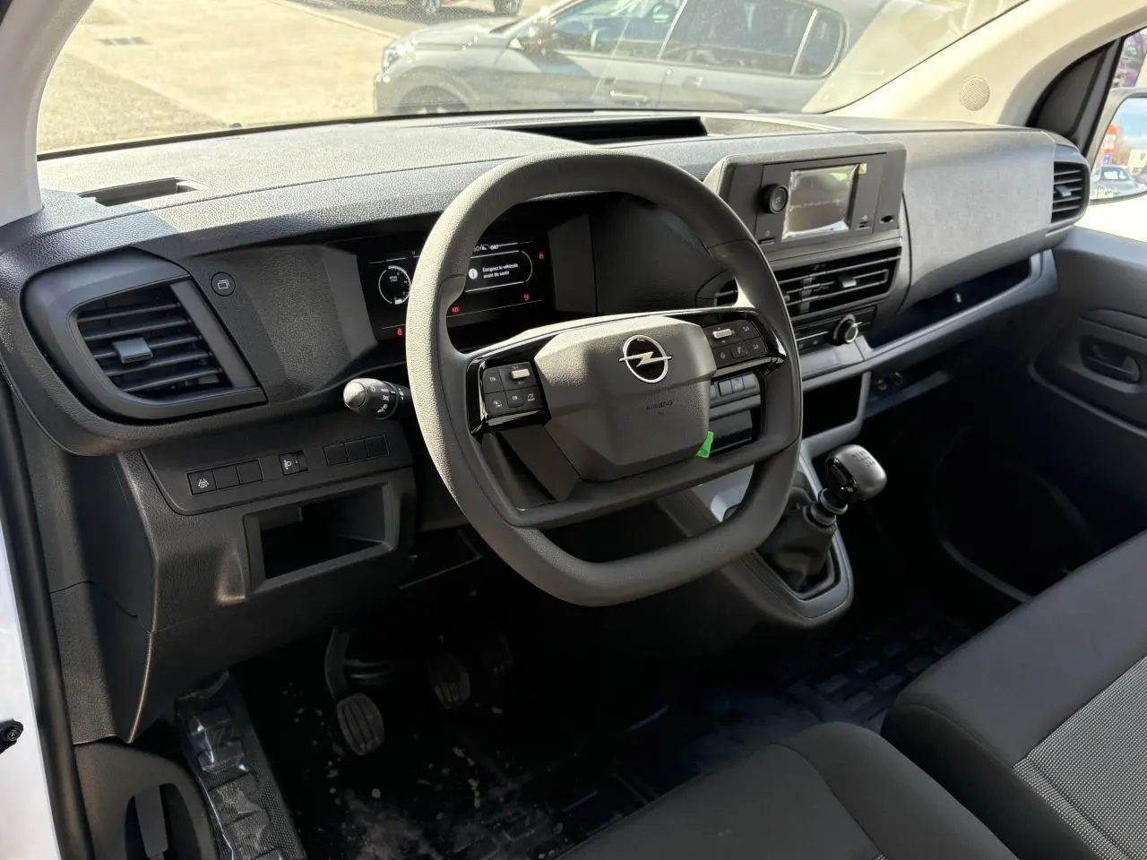 Intérieur du poste de conduite Opel Vivaro blanc 2024, vue côté conducteur sur volant multifonction et tableau de bord numérique.