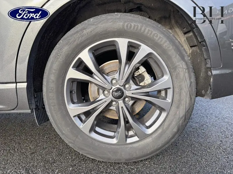 Gros plan sur la roue avant droite avec jante alu gris foncé du Ford Kuga 2023 Gris Magnetic Métallisée.