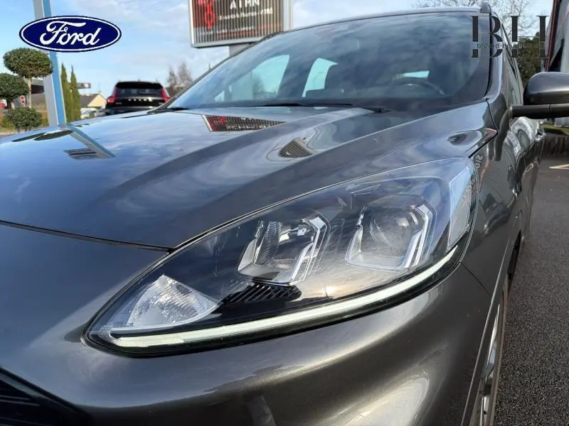 Gros plan sur le phare avant droit du Ford Kuga gris Magnetic Métallisé, mettant en valeur les lignes modernes du capot.