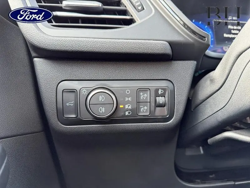 Détail du panneau de commandes d'éclairage noir à gauche du volant dans un Ford Kuga gris 2023.