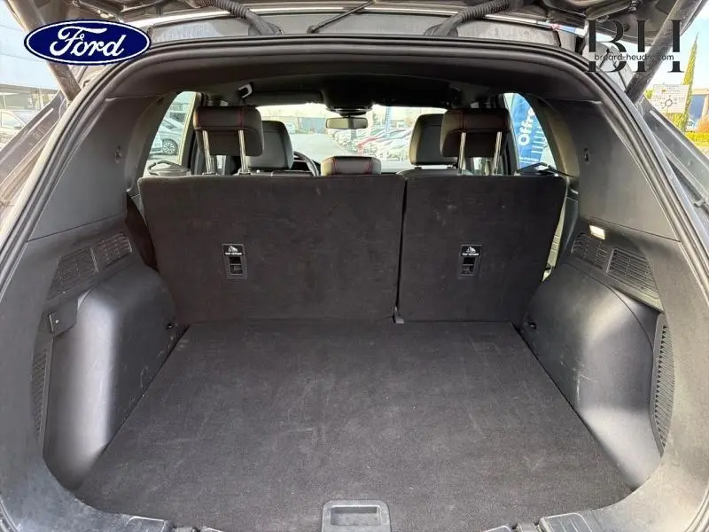 Vue arrière du coffre ouvert du Ford Kuga gris Magnetic Métallisée, montrant la banquette arrière en position verticale.