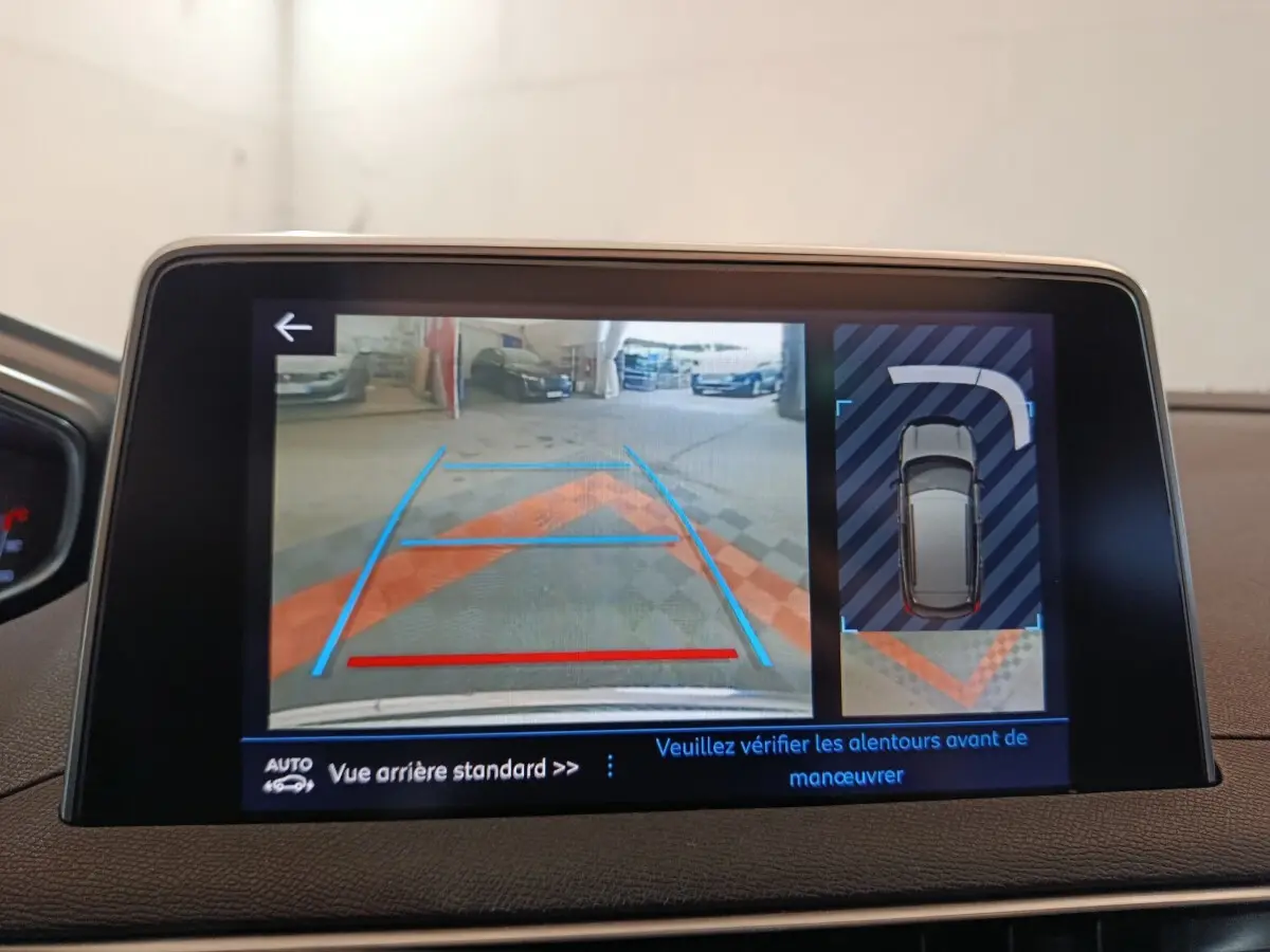 Écran tactile intérieur montrant la caméra de recul et l'aide au stationnement du Peugeot 3008 blanc.