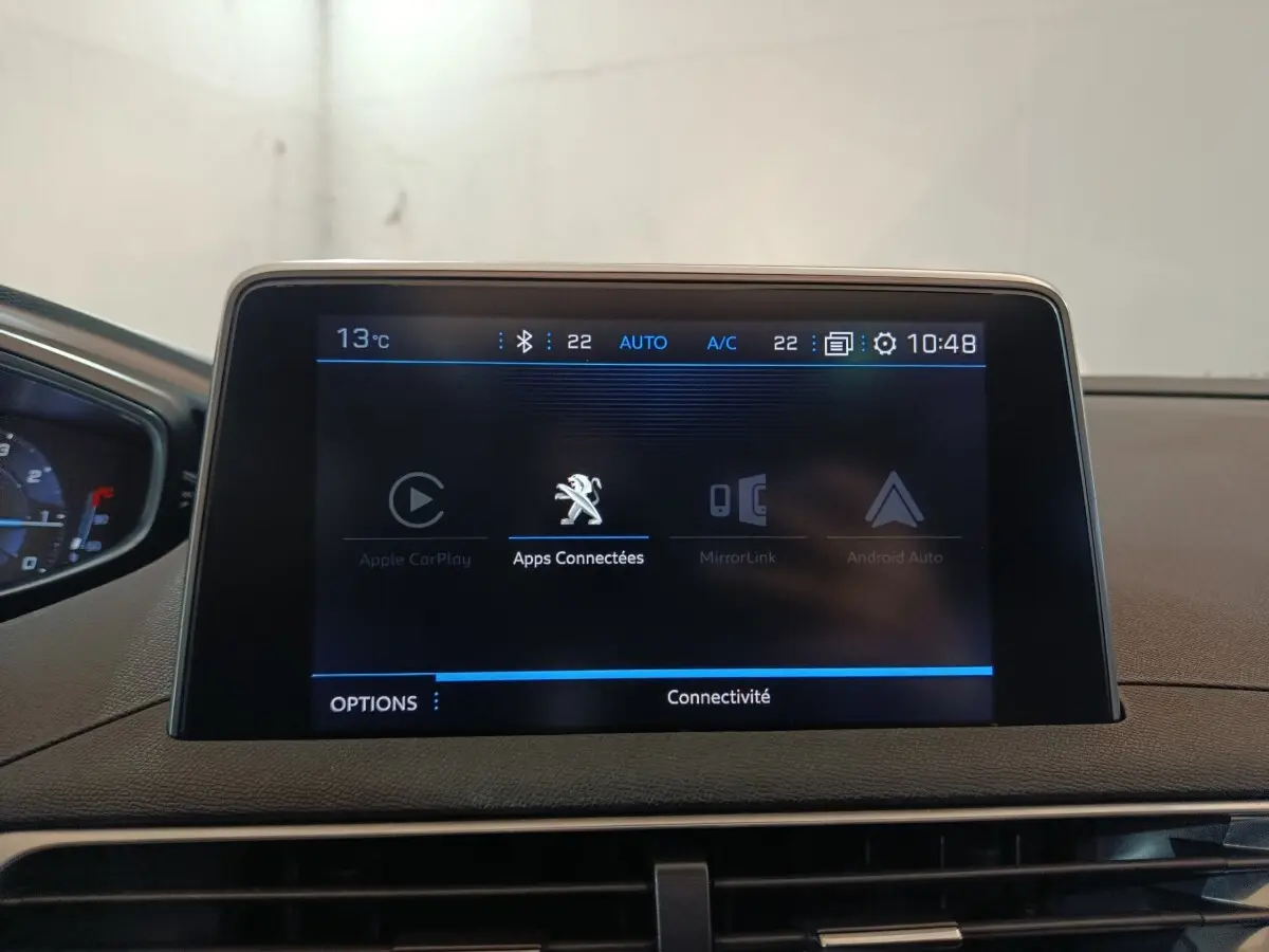 Écran tactile central affichant les applications connectées dans l'habitacle du Peugeot 3008 blanc, vue de face.