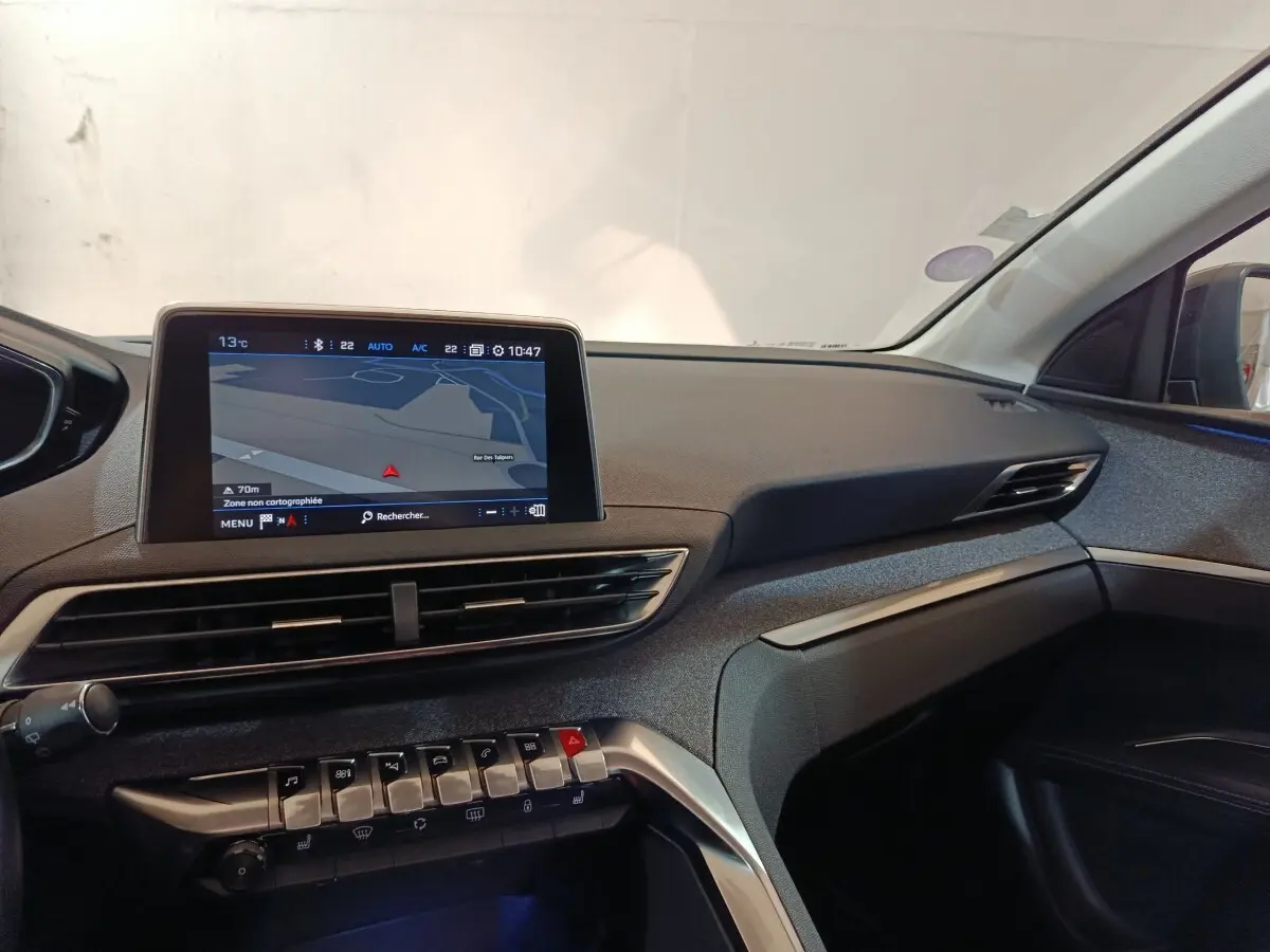 Vue intérieure côté passager du tableau de bord du Peugeot 3008 blanc, avec écran tactile de navigation allumé.
