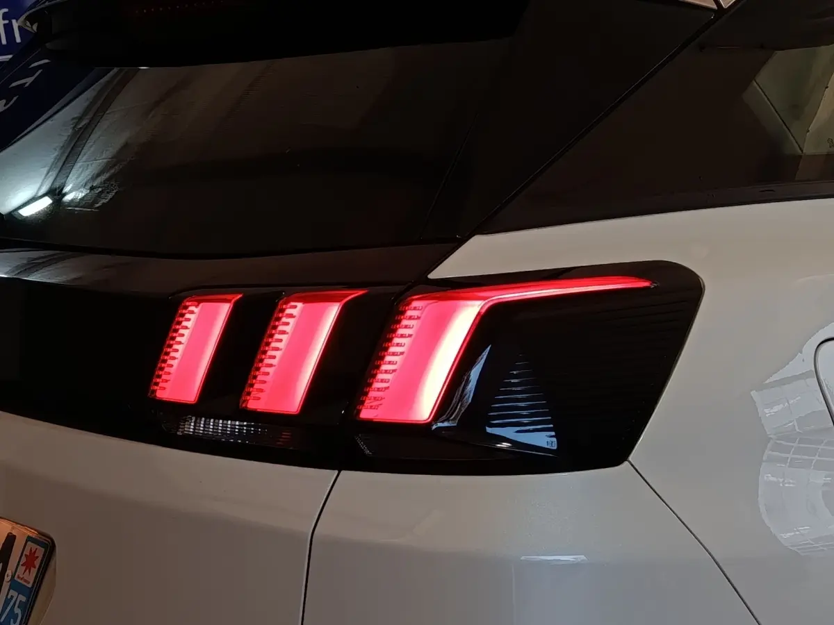 Feu arrière droit allumé d'un Peugeot 3008 blanc, vue rapprochée sur la partie arrière du véhicule.